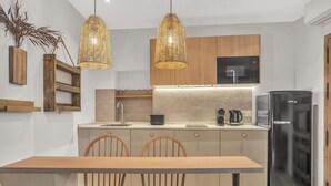 Een moderne keuken met houten kastjes, een zwarte koelkast en een eettafel met stoelen.