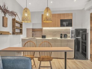 A modern kitchen with wooden cabinets, a black refrigerator, and a dining table with chairs. - Modern Studio in Malaga's Historic Heart (Málaga)