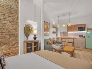 Een modern appartement met keuken, eethoek en woonkamer met een bank en een bed.