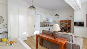 Una sala de estar moderna con un sofá, una mesa de madera y una cocina al fondo.