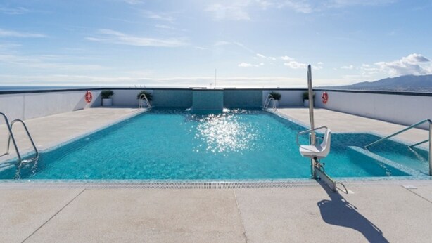 A swimming pool with clear blue water, surrounded by a concrete deck and metal railings, under a bright sun. - Elegant Accommodation in Malaga - Ideal for Groups (Málaga)