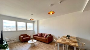 A spacious living area with a wooden floor, a brown sofa, a round coffee table, and a dining table with woven placemats. - Elegant Accommodation in Malaga - Ideal for Groups (Málaga)