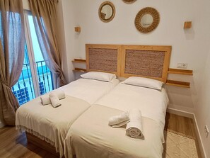 Ein Doppelbett mit zwei Kissen, einem hölzernen Kopfteil und einem Fenster mit Vorhängen.