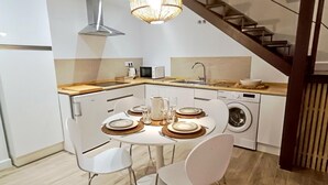 A modern kitchen with a dining table set for four, a washing machine, and a staircase. - Charming apartment in Malaga (Málaga)