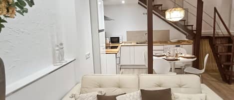 A modern interior with a sofa, a dining area, and a staircase.