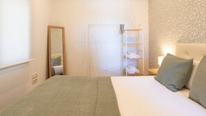 Una habitació d'hotel amb un llit, una zona de dutxa i un mirall.