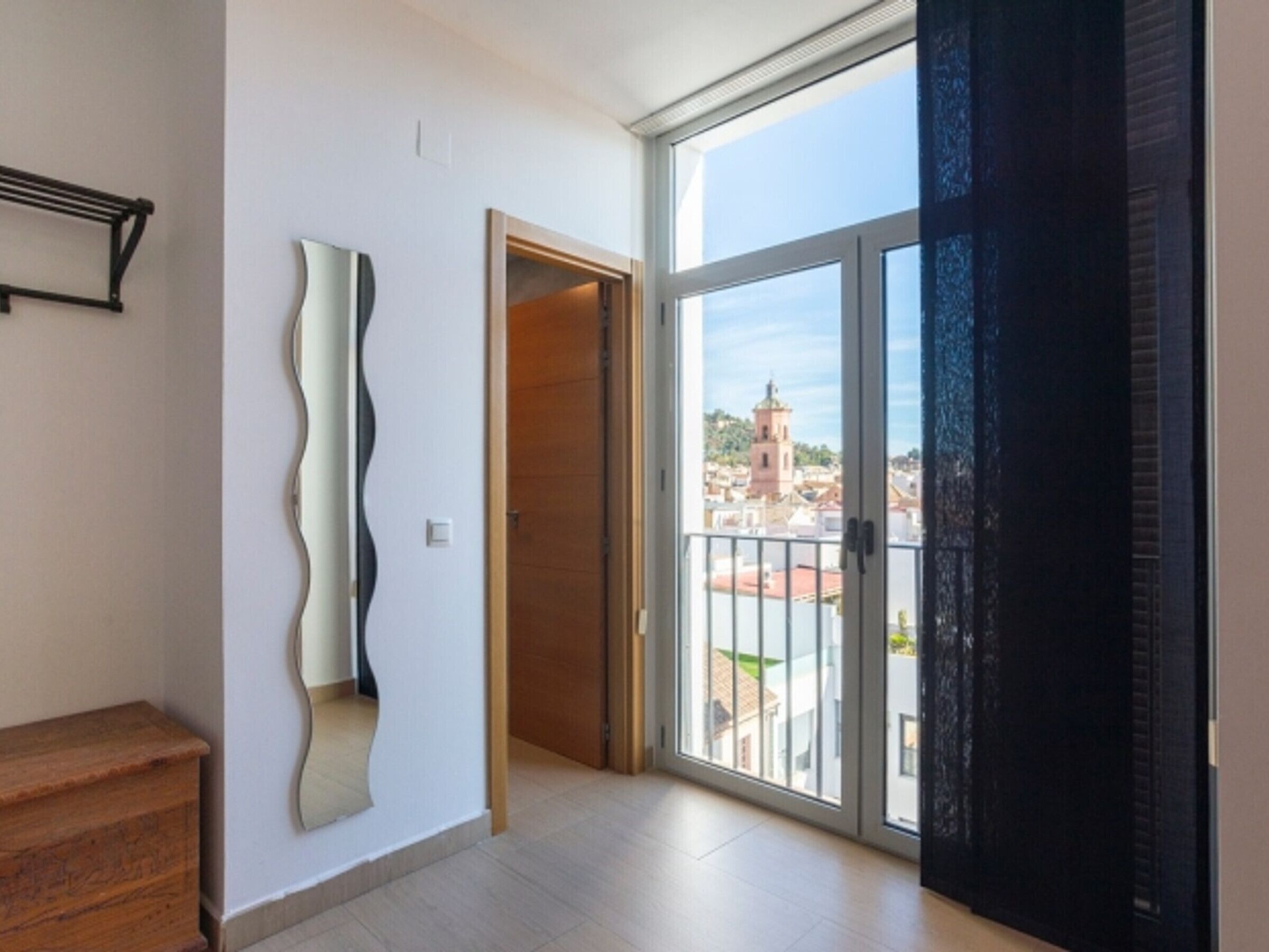 A spacious room with a large sliding glass door leading to a balcony with a city view.