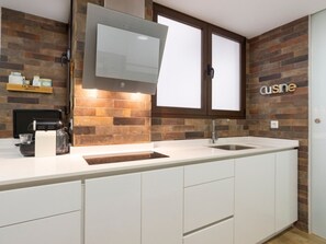 A modern kitchen with a brick backsplash, white cabinetry, a built-in oven, and a stainless steel sink. - Modern apartment in Malagueta, bright, 3 bdr, terrace with view (Málaga)