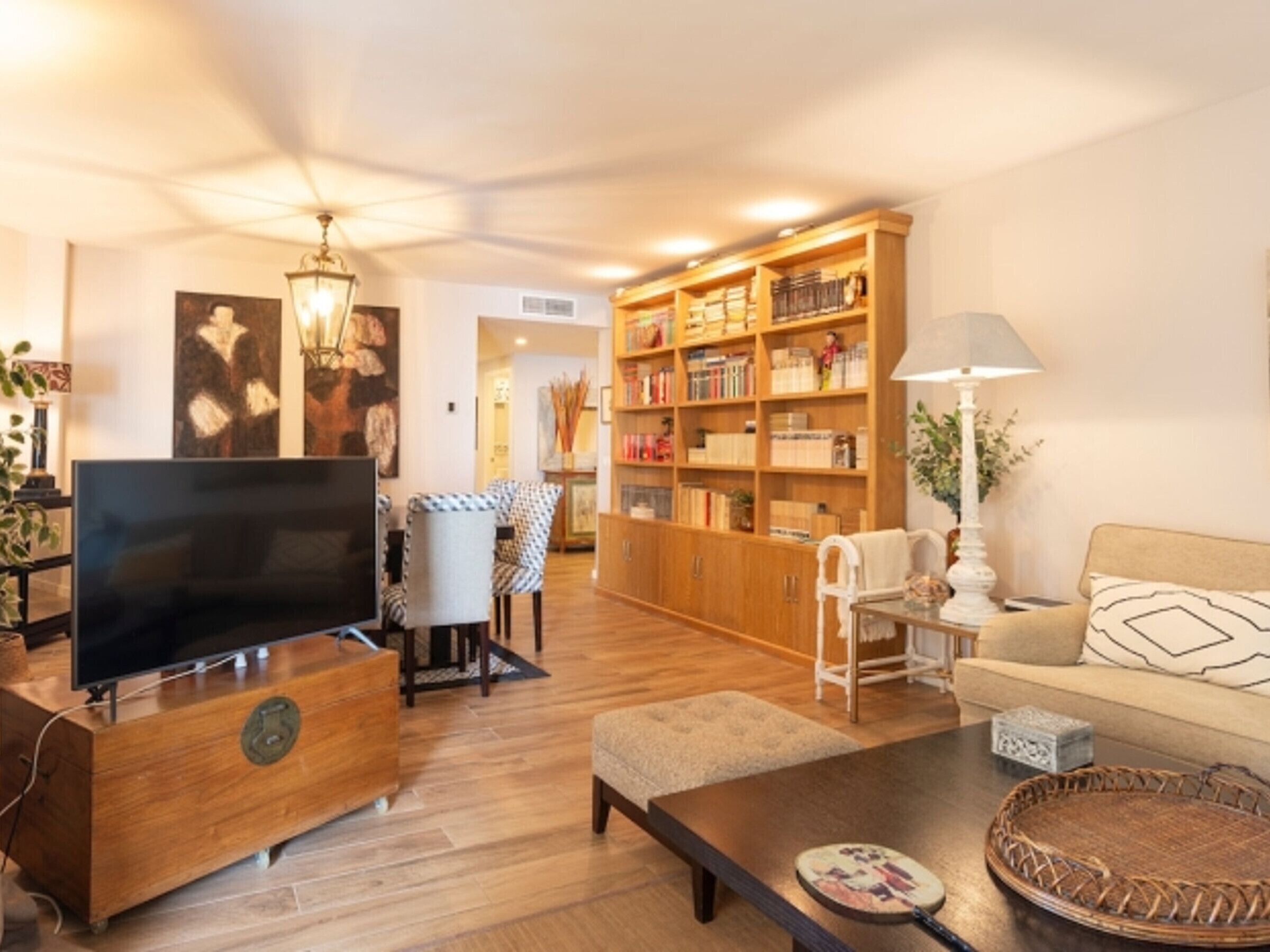 Ein Wohnzimmer mit Fernseher, Holzmöbeln, einem Bücherregal und einer Lampe.