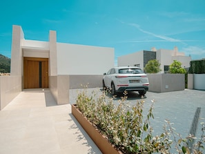 A modern building with a white facade, a wooden door, and a white car parked in front. - Luxury Villa in Mijas (Mijas)