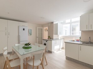 A modern kitchen with white cabinets, a glass dining table, and a built-in washing machine. - Stunning duplex in Malaga center with private terrace (Málaga)