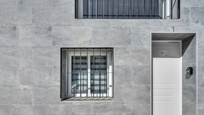 Facciata di un edificio moderno con un'ampia finestra con inferriate, una porta bianca e una piccola cassetta postale.