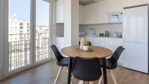 Un appartement moderne doté d’un coin repas, d’une cuisine et d’un grand balcon offrant une vue sur la ville.