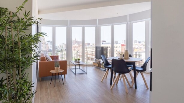 Un salon moderne avec de grandes fenêtres, un canapé, une table à manger et une plante en pot.