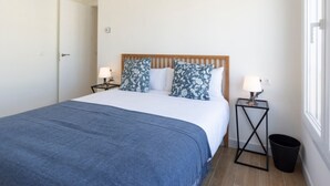 Une chambre à coucher avec un lit, deux tables de chevet, une tête de lit en bois et une fenêtre.