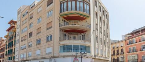 Um hotel de vários andares com fachada em curva, grandes janelas e uma loja no térreo.