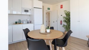 Une cuisine moderne avec des meubles blancs, un four à micro-ondes et un petit coin repas comprenant une table ronde et quatre chaises.