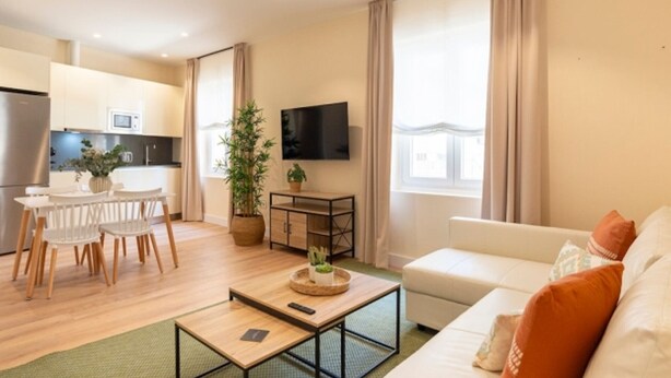 Ein modernes Wohnzimmer mit einer Couch, einem Couchtisch und einem Essbereich mit Stühlen und einem Tisch.