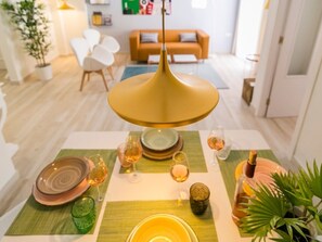 A dining table set with plates, glasses, and a bottle, in a modern living room with a sofa and chairs. - Modern 2-bedroom apartment in Malaga center (Málaga)