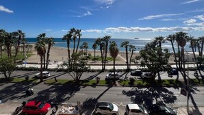 En parkeringsplats med bilar, palmer och utsikt över stranden och havet.