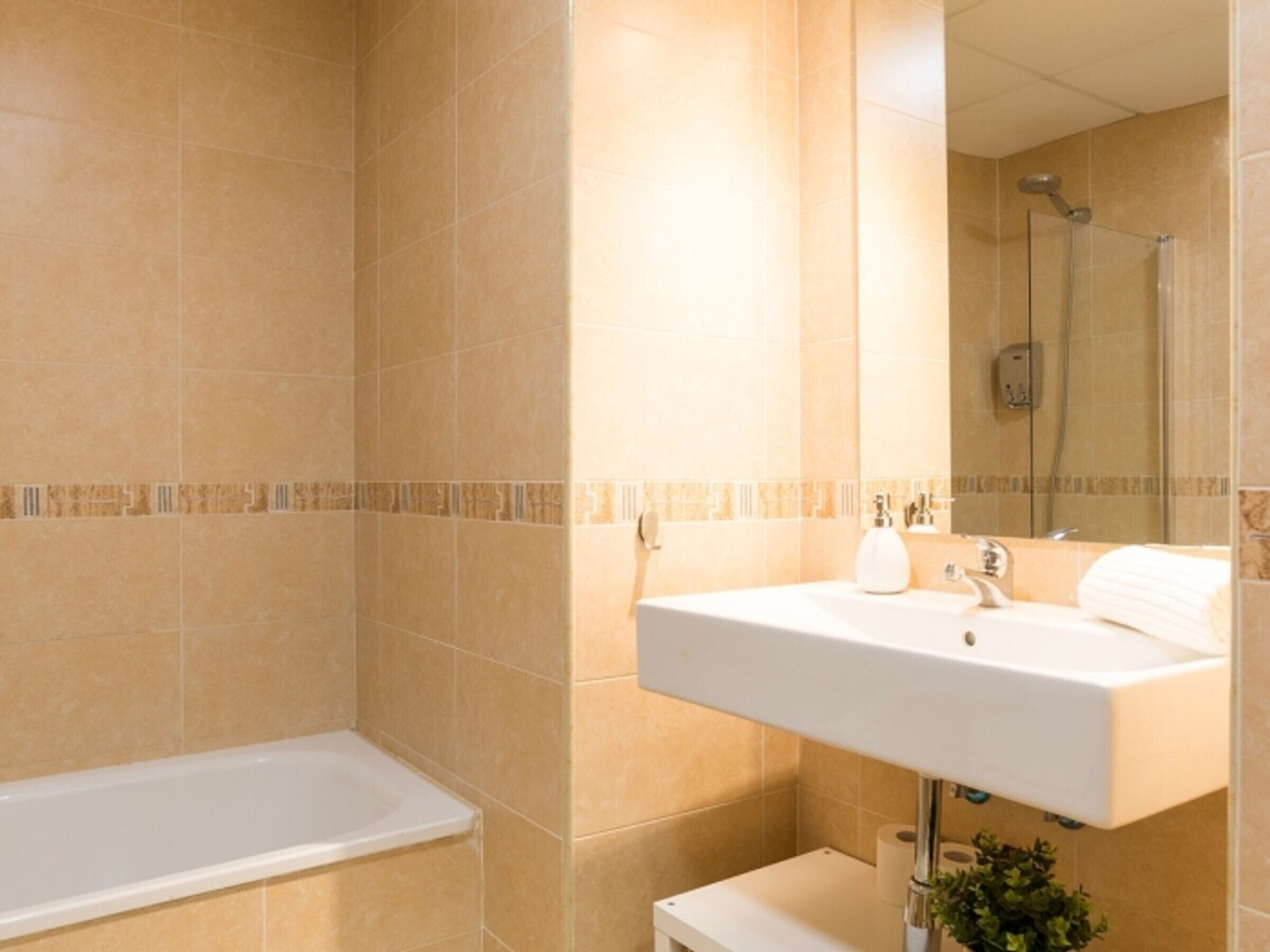 Een badkamer met een bad, een wastafel en een douche.