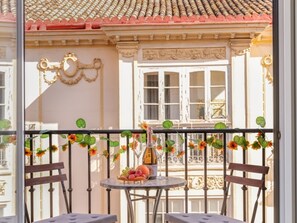 Un balcó amb una taula preparada per a dues persones, una ampolla i un plat de fruita.