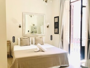 A hotel room with a bed, a large mirror, a door to the outside, and a wall-mounted light fixture. - Traditional Apartment in Malaga Center with Balconies (Málaga)