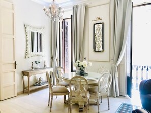 A dining area with a round table, chairs, a chandelier, and a view of the outdoors. - Traditional Apartment in Malaga Center with Balconies (Málaga)