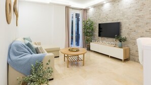 Ein modernes Wohnzimmer mit einer Couch, einem Couchtisch, einem Fernseher und einer Ziegelwand.