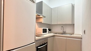 Una cocina compacta con refrigerador, microondas, horno y lavaplatos.