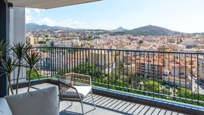 En balkon med udsigt over bybilledet, inklusive bygninger og en bakke.