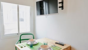 A small dining area with a table, chairs, and a TV mounted on the wall. - Modern Studio in Soho, Malaga (Málaga)