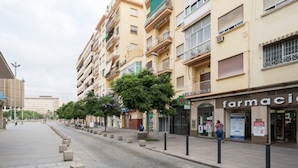 A street with a pharmacy on the right, a row of trees, and a building in the background. - Modern Studio in Soho, Malaga (Málaga)