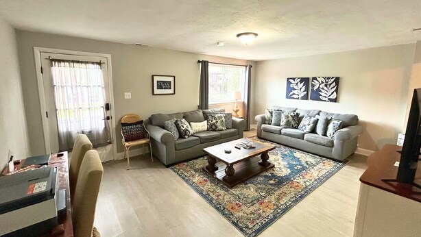 A living room with two grey sofas, a coffee table, a patterned rug, and a chair with a cushion. - Comfortable Westerville Apt by State Street - Great for Mid-Term, Prime Location (Westerville)