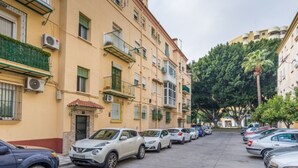 A row of parked cars along a street lined with multi-story buildings, some with balconies and air conditioning units. - Bright 3-bedroom apartment in the heart of Málaga (Málaga)