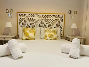 Una habitación de hotel con una cama grande, dos mesitas de noche y un cabecero decorativo.