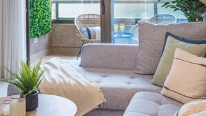 Una sala de estar moderna con un sofá gris, una mesa redonda de madera y una planta en maceta.