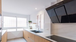 Una cocina moderna con armarios de madera, una placa de inducción negra y un ventanal que proporciona luz natural.