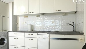Cozinha compacta com armários brancos, lava-louças Bosch e uma pia com torneira moderna.