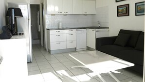 Cozinha moderna com armários brancos, lava-louças e um espaço de refeições com mesa branca.