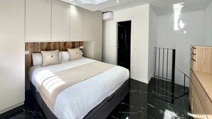 Ein modernes Schlafzimmer mit einem großen Bett, integriertem Kleiderschrank und ansprechendem Deckenstil.