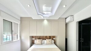 Ein modernes Schlafzimmer mit einem großen Bett, einer eingebauten Kopfteil und einer Deckenleuchte.