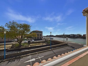 A waterfront view with a building, parked cars, and a clear sky. - Bright apartment with terrace, near beach and shops (Le Grau d'Agde)