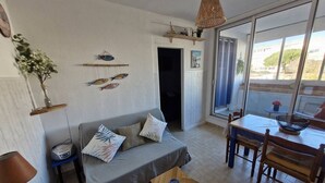 Ein Wohnzimmer mit einer Couch, einem Esstisch und einem großen Fenster.