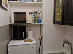 Eine kleine Küche mit Mikrowelle, Kaffeemaschine und kleinem Kühlschrank.