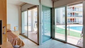 Een moderne hotelkamer met een grote schuifglazen deur die uitkomt op een balkon met uitzicht op het zwembad.