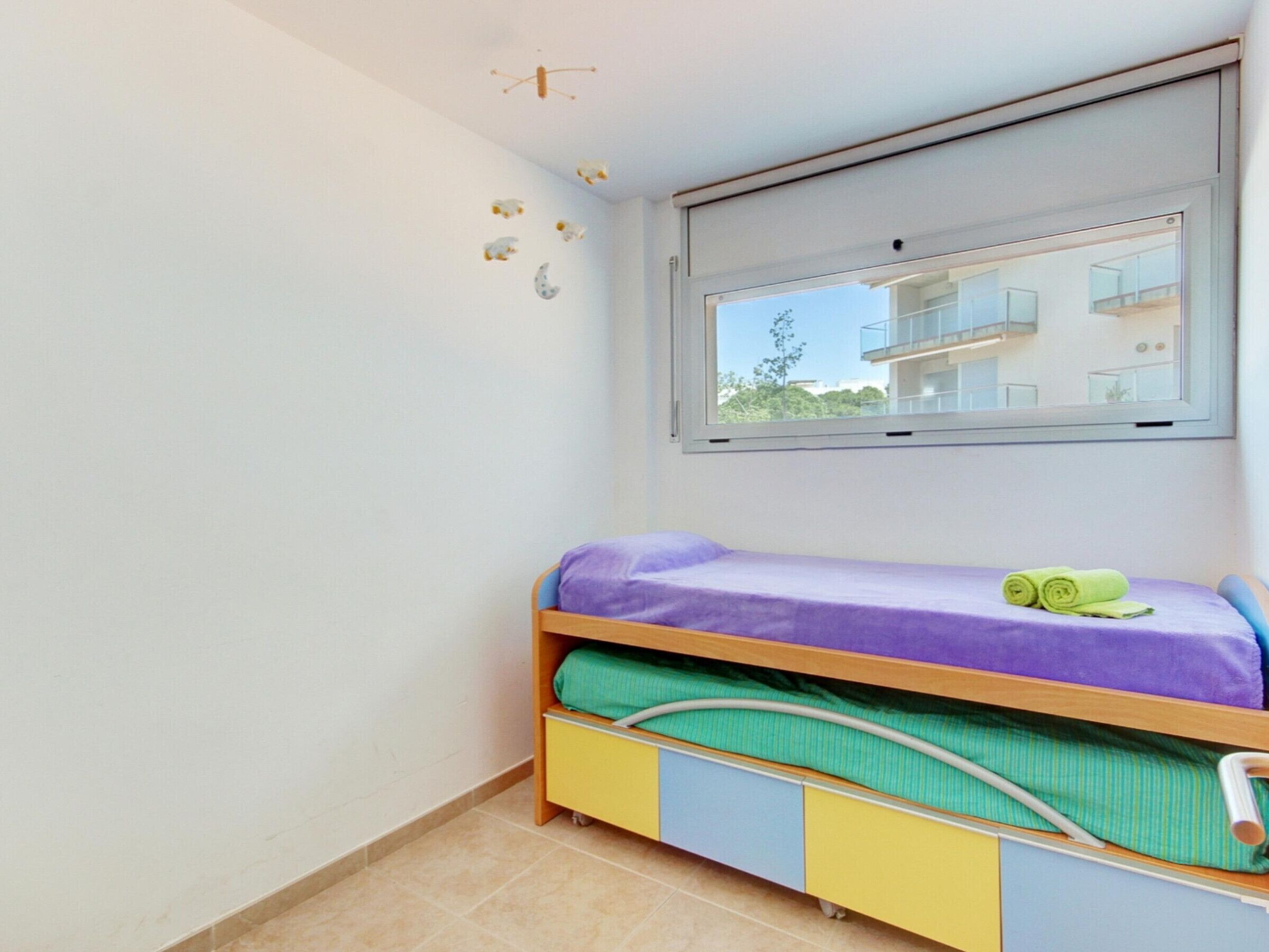 A child's bedroom with a bed, a window, and a view of a building outside.