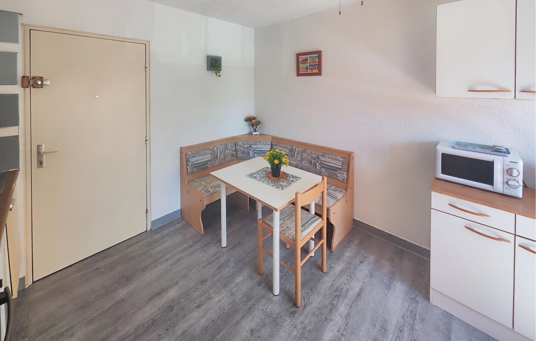 A small kitchen with a table and bench, a microwave, and cabinets.