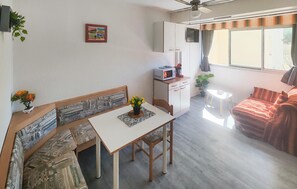 Ein kompakter Wohnraum mit Essbereich, Küchenzeile und einer Couch.