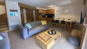 A modern living room with a sofa, coffee table, and dining area with chairs and a table. - 4-Bedroom Duplex with Balcony and Parking in Valmorel (Valmorel)